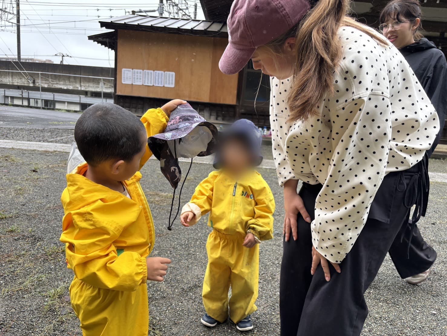 An intern with children in raincoats on a rainy day