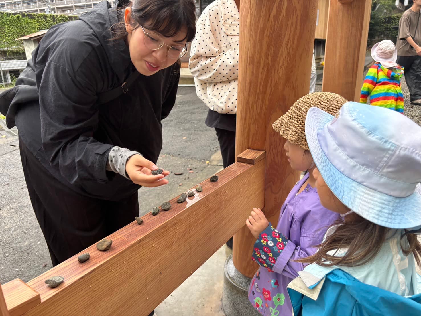 Lining up small stones with children at a shrine